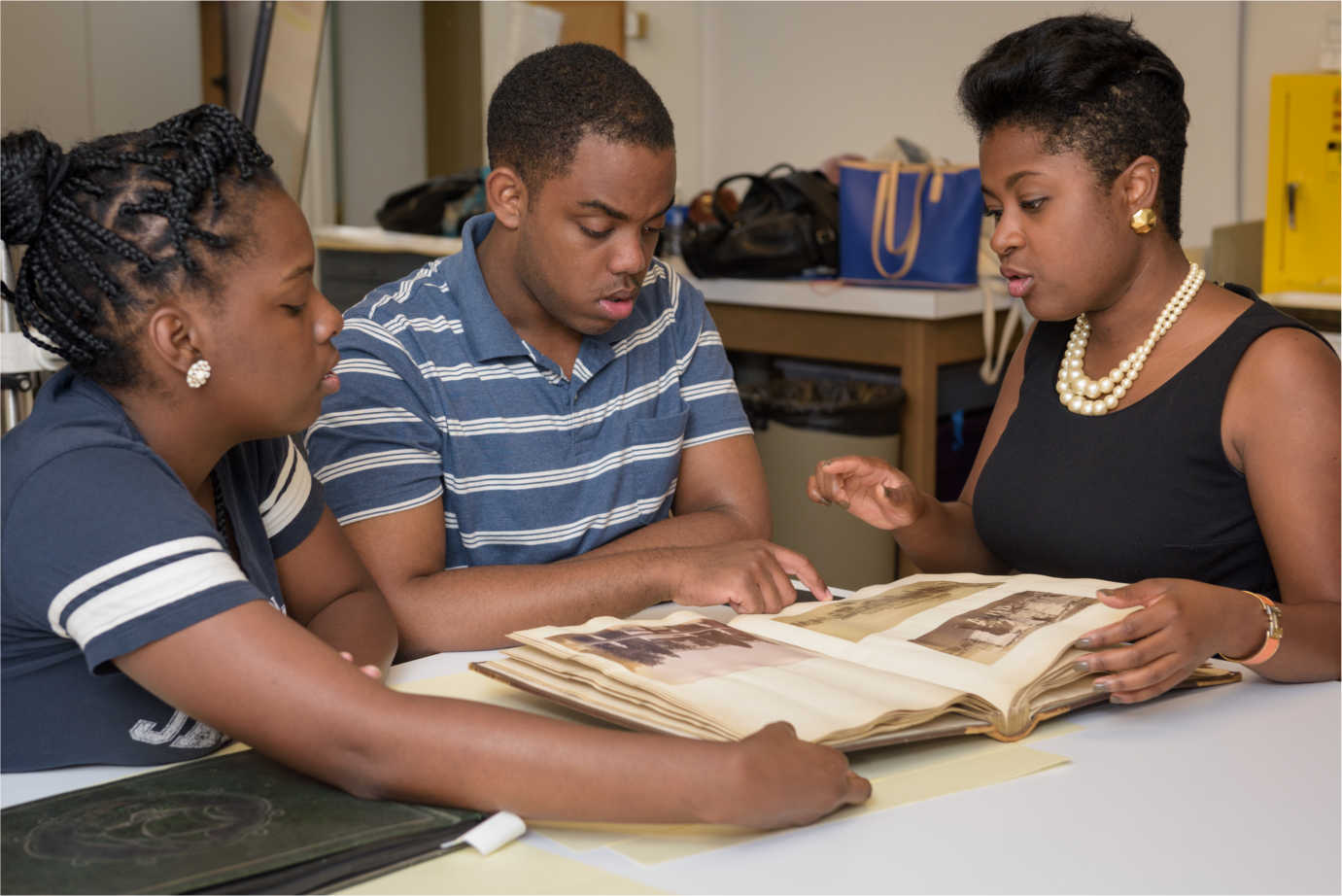A third-year Master&rsquo;s student in the Winterthur/University of Delaware Program in Art Conservation (left) examines a 19th-century photographic album with two students during a UD seminar focused on the preservation of the rich and varied photographic collections in historically black colleges and universities. Image courtesy of Evan Krape, University of Delaware.